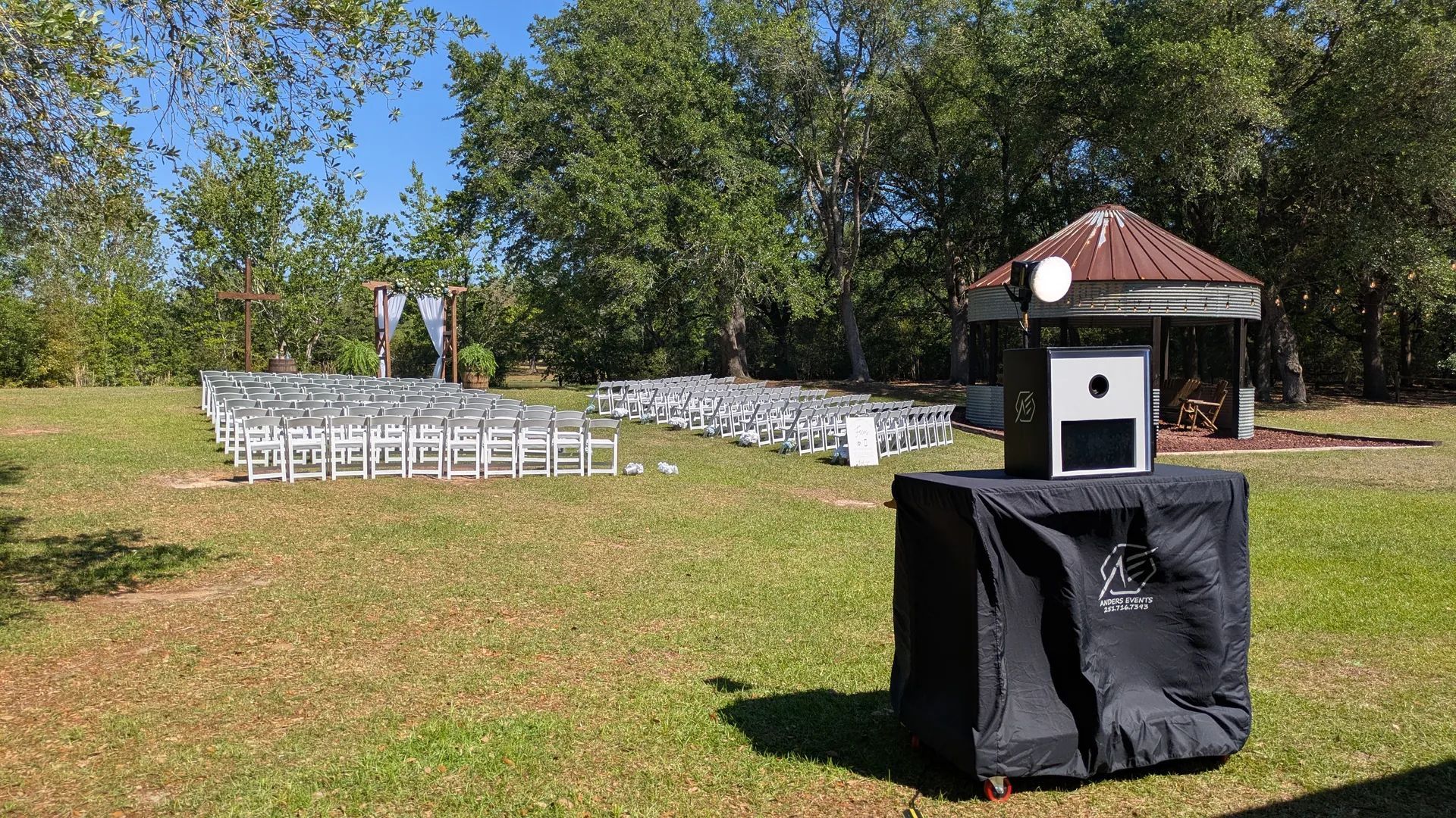 The photo booth standing on open lawn at an outdoor wedding ceremony with no cables running to it.